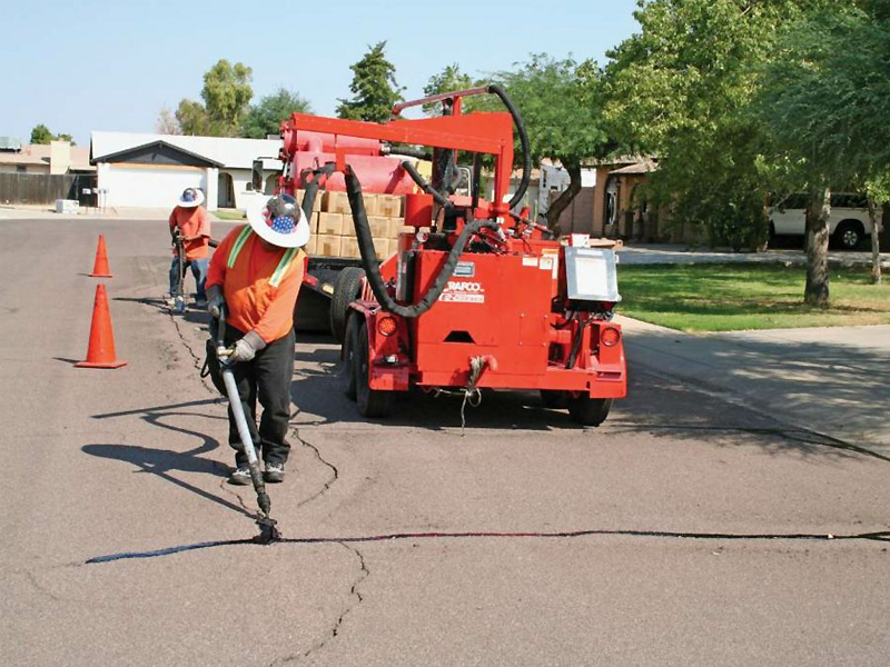Summit employees apply sealant and asphalt surface treatment to the road to seal cracks and damage to the roadway.